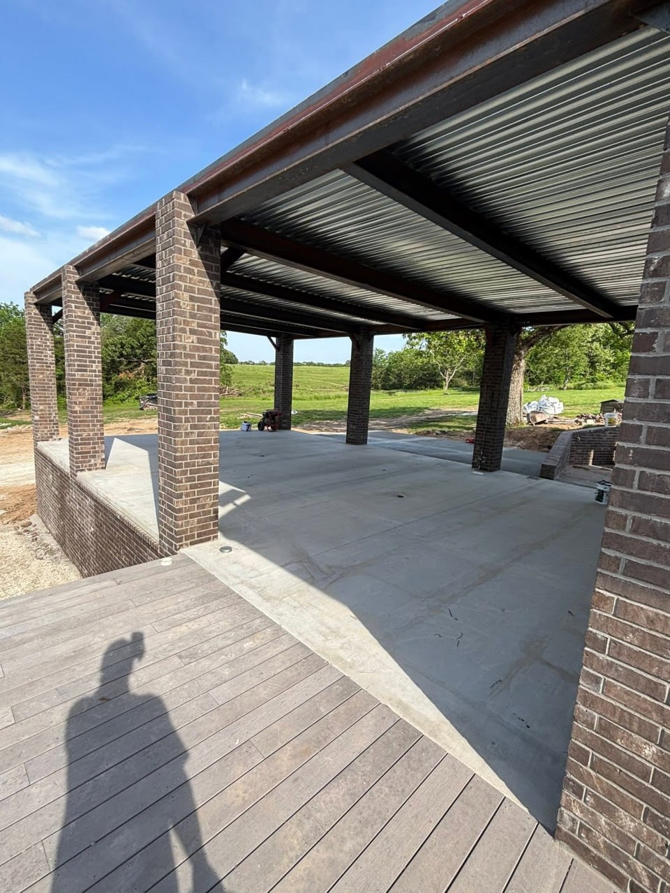 Covered structure with brick columns, steel beams, metal roof decking, and concrete floor